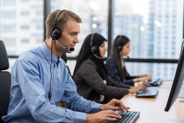 Happy Smiling Operator Customer Service Agent With Headsets Working On A Computer In A Call Center, Talking With The Customer For Assisting To Resolve The Problem With Her Service Mind